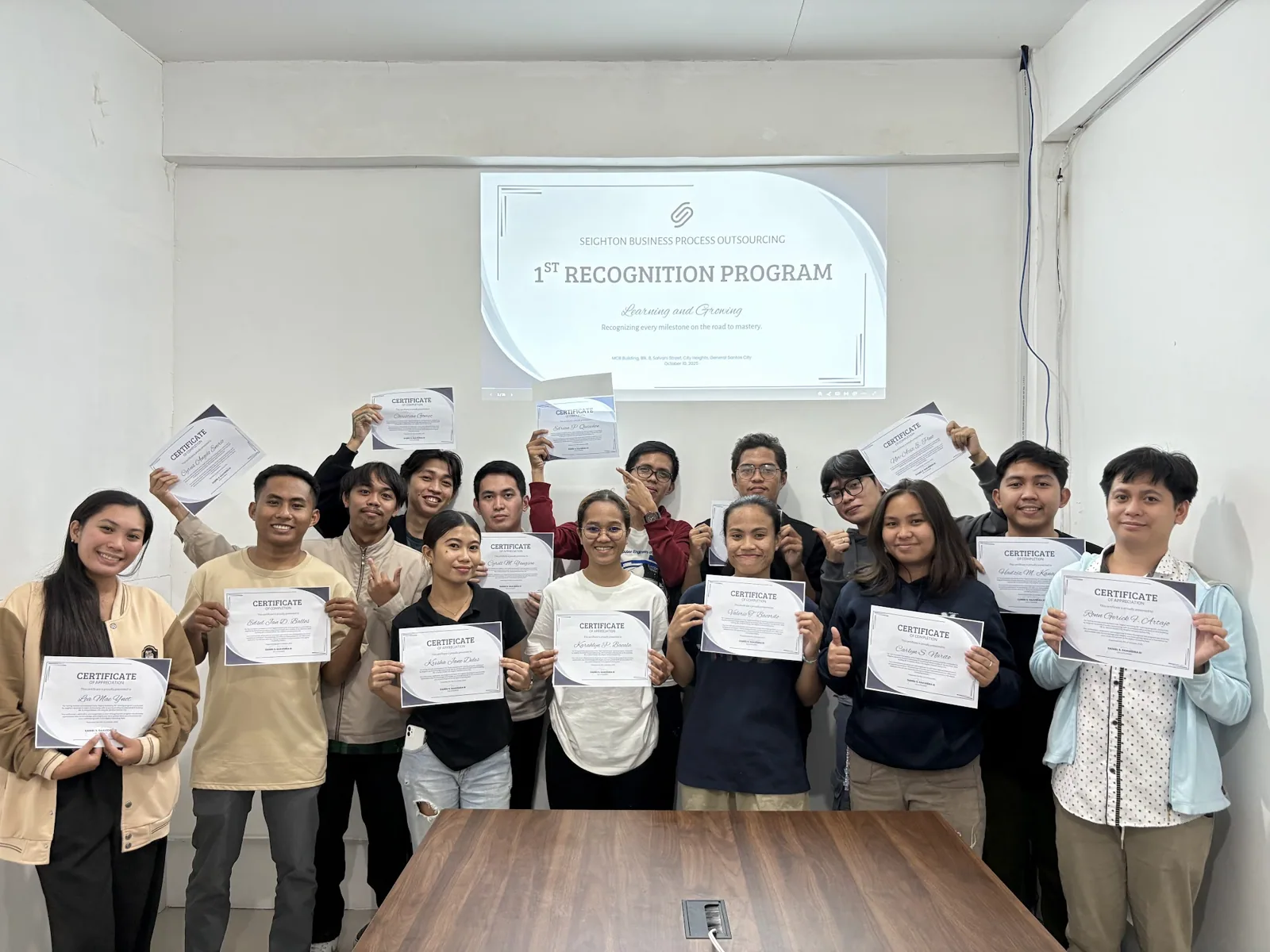 A training batch holding their certificates of completion at the Seighton recognition program